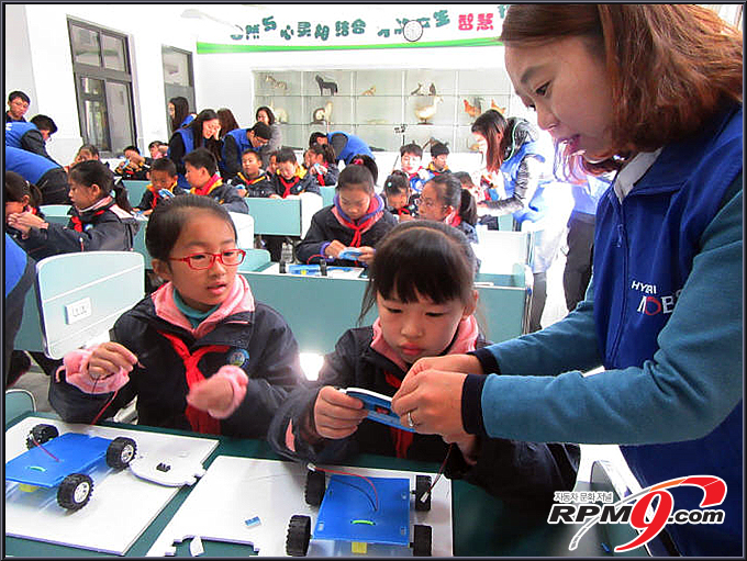 중국 상해 송강구 구정 소학교에서 상해모비스 직원 자원봉사자들이 학생들을 도와 `장애물을 만나면 멈추는 자동차` 실습을 진행하고 있다. <사진=현대모비스>