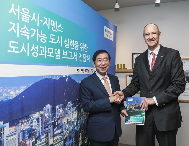 27일 오후 서울 시청에서 열린 '도시성과모델 보고서' 전달식에서 롤랜드 부시 독일지멘스 부회장(오른쪽)과 박원순 서울시장(왼쪽)이 기념 촬영을 하고 있다.