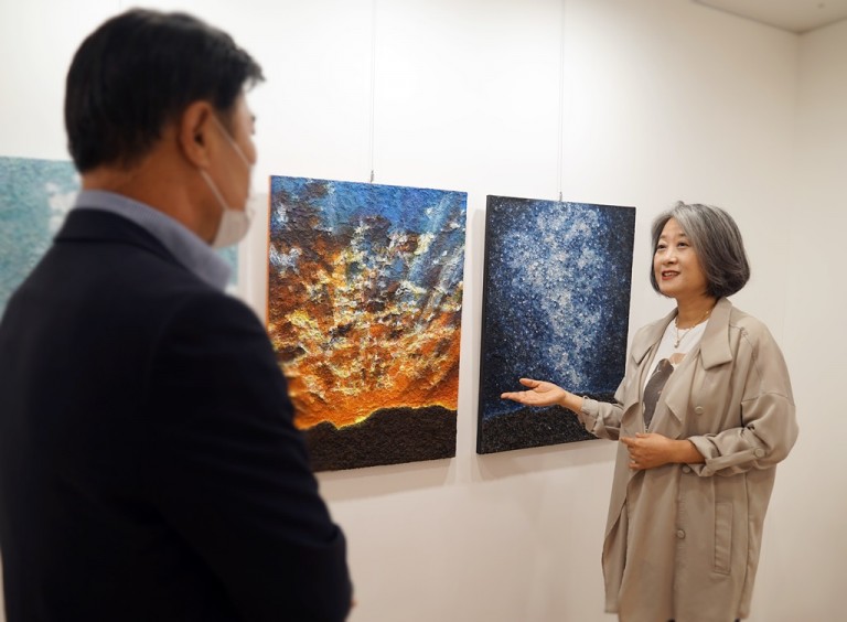 윤경 작가(오른쪽)가 유디갤러리를 찾은 관객에게 작품을 설명하고 있다.