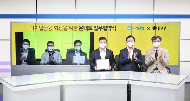 우리은행과 카카오페이가 10일 원격화상회의를 통해 업무협약을 체결한 후 기념 촬영을 하고 있다. 권광석 우리은행장(왼쪽 네번째)과 류영준 카카오페이 대표(세번째)가 협약서를 들어보이고 있다.