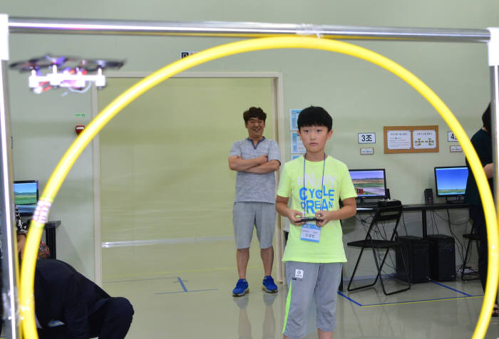 학생들이 직접 만든 드론을 띄워 훌라후프 장애물을 통과시키고 있다. 김동욱기자 gphoto@etnews.com