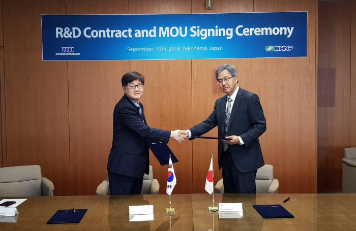 손순환 한국수력원자력 중앙연구원 방사선환경연구소장(왼쪽)과 이사무 오노 IHI 원자력분야 전무가 후쿠시마 원전 사고로 발생한 방사성폐기물 유리화 실증연구 계약 및 MOU에 서명한 뒤 악수를 하고 있다.