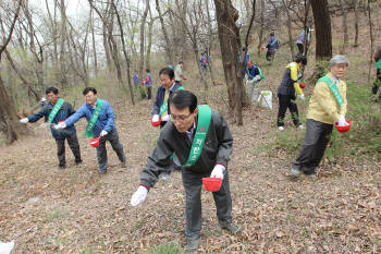 남상건 LG상록재단 부사장(사진 맨 앞)을 비롯한 행사 관계자들이 18일 서울 일자산에서 토양개량제를 뿌리고 있다.