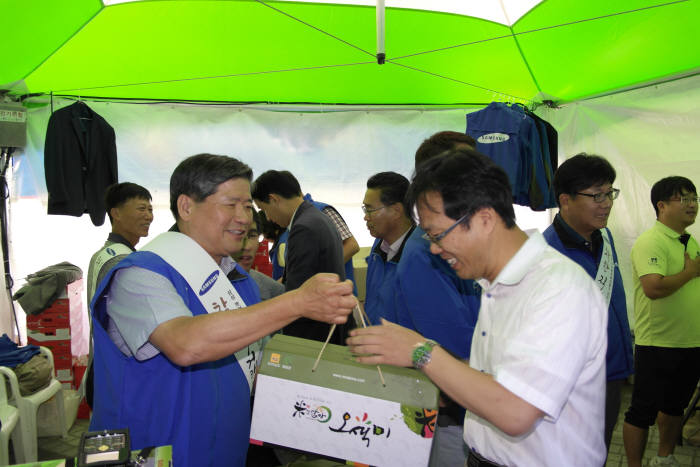 손석원 삼성토탈 사장(왼쪽)이 농촌 자매마을 전남 화순 평리마을 주민들과 함께 연 직거래 장터 일일가게 점장으로 나서 특산물 홍보와 판매를 하고 있다.