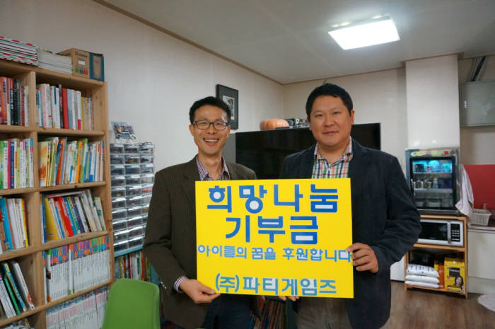 서현석 파티게임즈 이사(오른쪽)가 흥덕지역아동센터 대표인 김승민 목사에게 희망나눔 기부금을 전달했다.