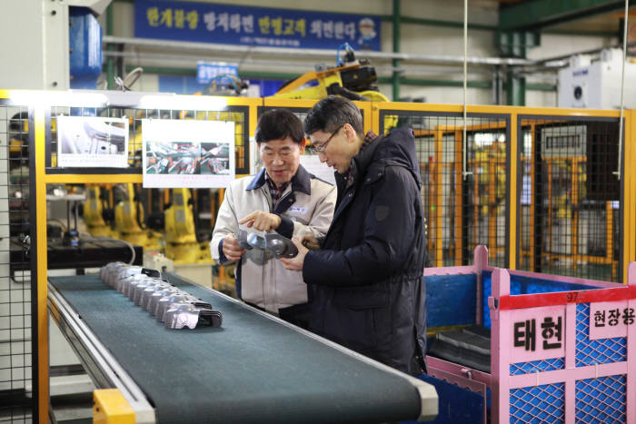 경진호 한국기계연구원 중소제조업용로봇시범사업추진단장(오른쪽)이 수요기업인 태현의 현수호 대표로부터 로봇보급 사업을 통해 생산된 제품 설명을 듣고 있다.