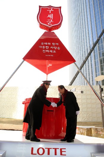 이인원 롯데그룹 부회장(오른쪽)이 대형 구세군 냄비에 기부금을 넣고 박종덕 한국구세군 사령관과 악수했다.