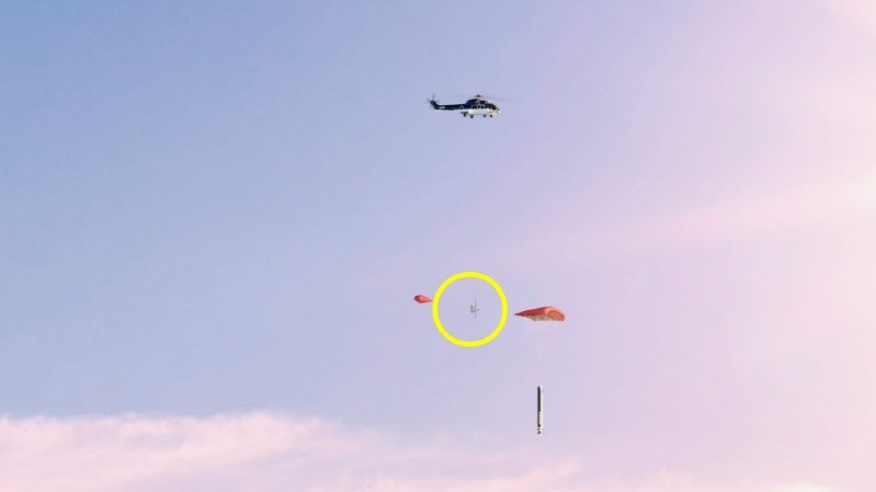 특수 갈고리(노란색 원)로 주낙하산과 보조낙하산 사이 줄을 잡아채는 시뮬레이션 이미지. 사진=로켓 랩