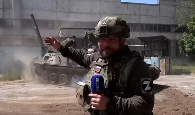 Pro-Russian journalist Aleksandr Coats delivers news in front of a Russian military mortar.  Daily Mail capture.