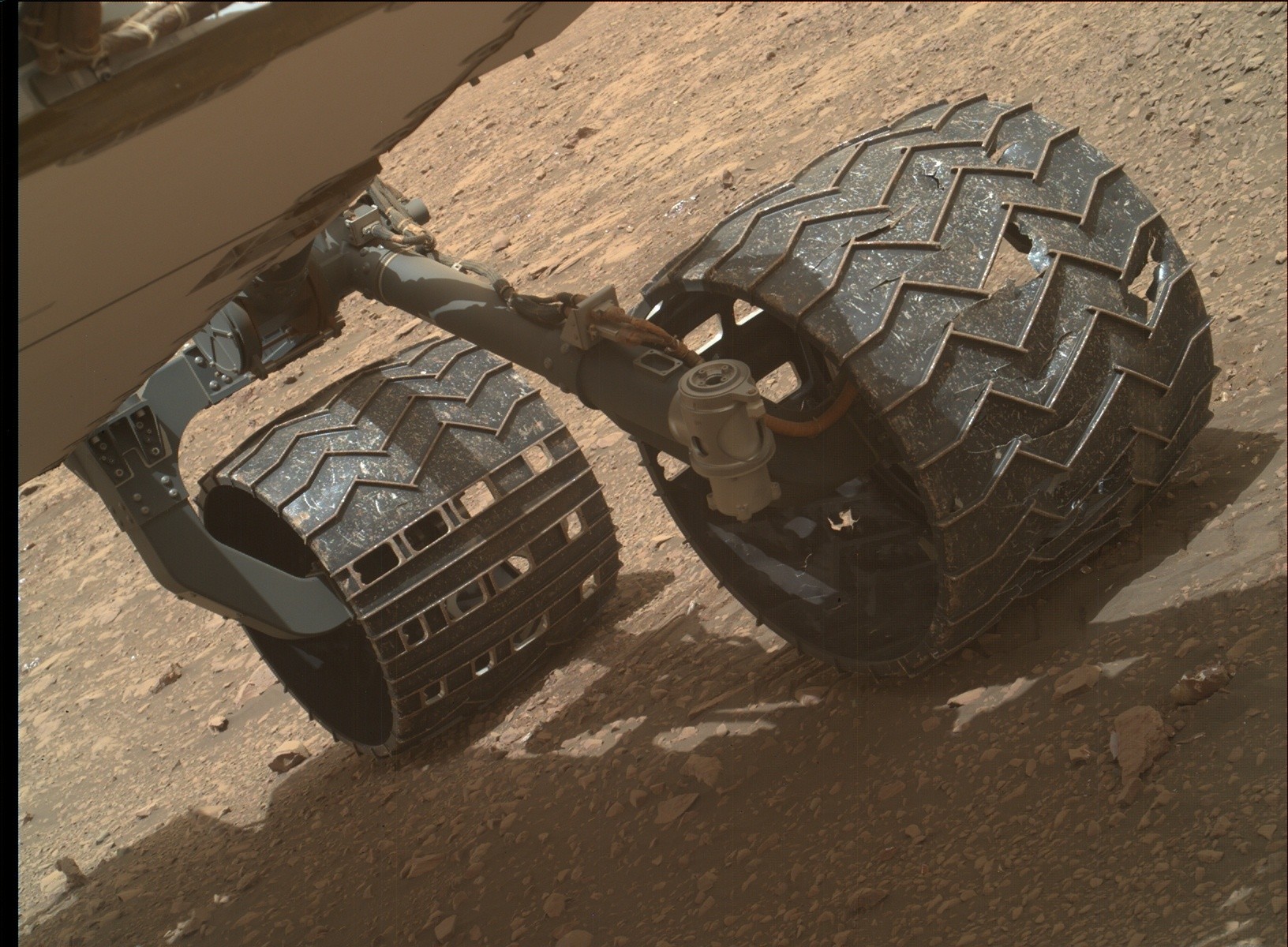 The wheels of the Curiosity Rover have been damaged over the years.  NASA suspects that some of the broken wheels may be scattered along the rover's track.  Photo = NASA/JPL-Caltech