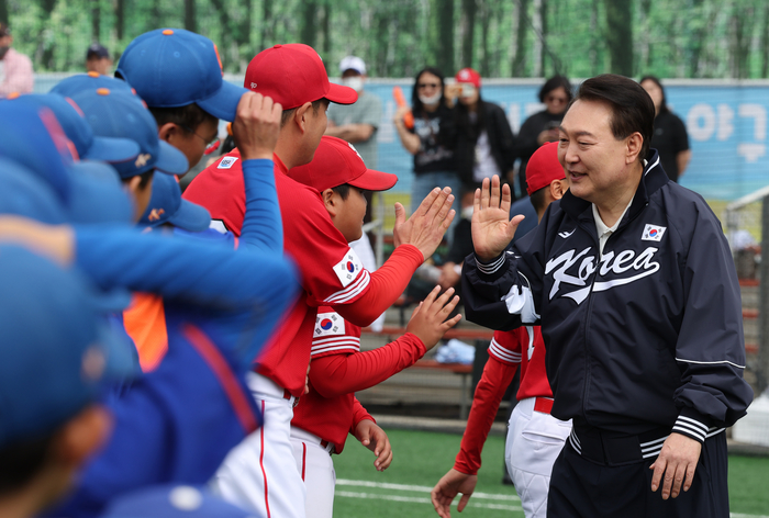 윤석열 대통령이 휴일인 14일 서울 용산 어린이정원 내 어린이야구장에서 열린 2023 대통령실 초청 전국 유소년 야구대회 서울 가동초- 대전 신흥초 결승 경기에 앞서 어린이 야구선수들과 손을 마주치며 격려하고 있다.  연합뉴스