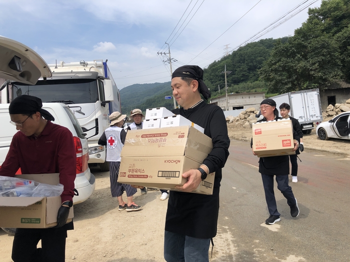 교촌에프앤비 임직원 봉사단과 교촌치킨 가맹점주들이 경북 예천군 감천면 수해현장에 방문해 치킨 나눔 활동을 진행하고 있다.