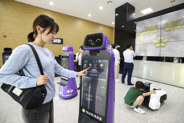 청남대 대통령기념관에서 관람객들이 안내로봇에게 관람 정보를 안내받고 있다.