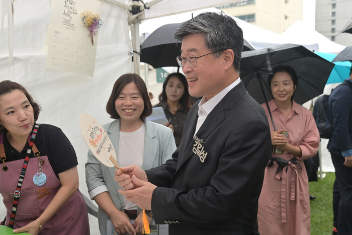 김길성 서울 중구청장이 지난 13일 중구청에서 진행된 일자리박람회와 사회적경제축제 '내:일 바람'의 부대행사로 열린 사회적경제기업들의 플리마켓에서 제품을 구입하며 웃고 있다. 사진=중구