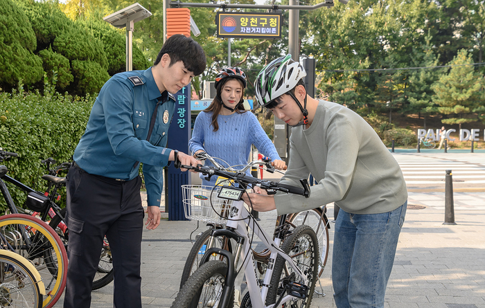 서울 양천구 목동 자전거 지킴이존에서 한 구민이 경찰의 도움을 받아 전자칩이 내장된 자전거 번호판을 장착하고 있다. 사진=양천구