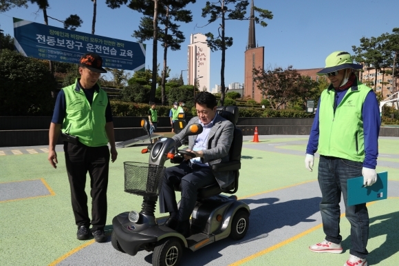 박 구청장(가운데)이 지난해 전국에서 처음 조성한 '전동 보장구 운전 연습장'에서 전동 보장구를 직접 운전하고 있다. 사진=관악구