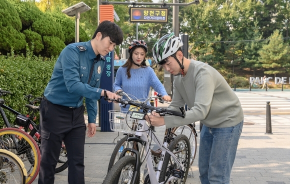 서울 양천구 목동 자전거 지킴이존에서 한 주민이 경찰의 도움을 받아 전자칩이 내장된 자전거 번호판을 장착하고 있다. 사진=양천구