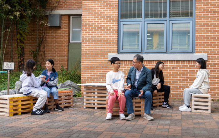 목동초등학교 교장 선생님과 학생들이 볼보 파빌리온 친환경 가구에 앉아 대화를 나누고 있다.