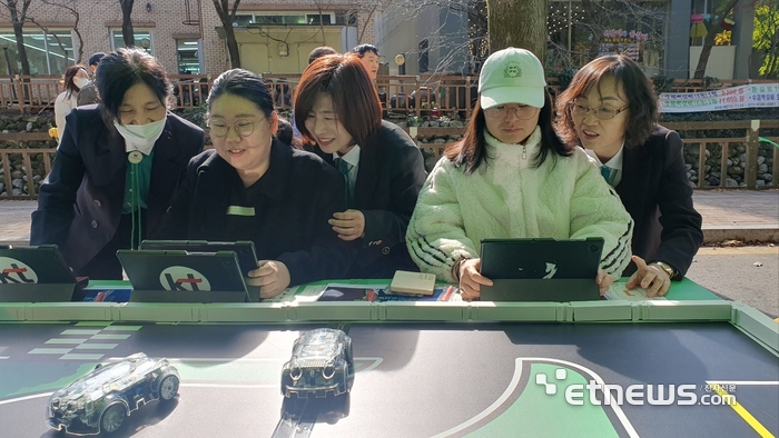 청소년들이 KT의 AI 자율주행 자동차 교구 '알티노' 코딩을 체험하는 모습.