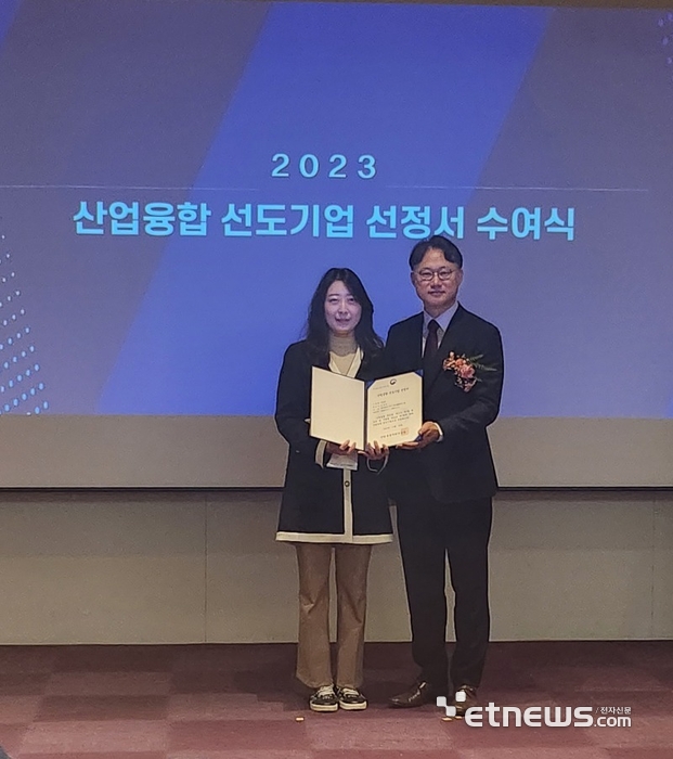 권소은 오톰 상무(왼쪽)가 산업부 관계자로부터 '2023 산업융합 선도기업' 선정서를 받은 뒤 기념촬영하고 있다.