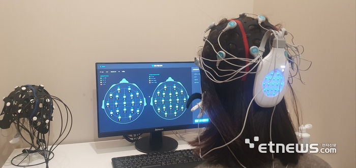 본지 송혜영 기자가 와이브레인 마인드스캔으로 뇌파 측정 준비를 하고 있다. 모자를 쓰면 뇌파 전극 수치를 확인할 수 있다.