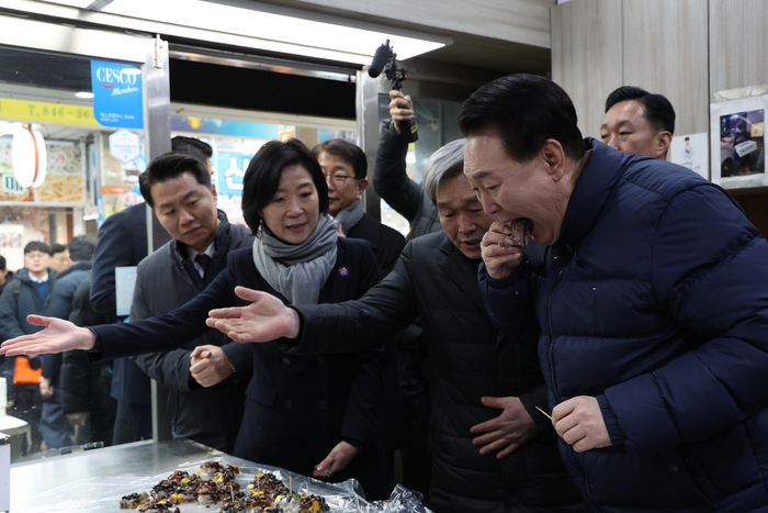 윤석열 대통령이 25일 경기도 의정부시 의정부제일시장을 찾아 떡 가게에서 상인이 건넨 떡을 맛보고 있다. 연합뉴스