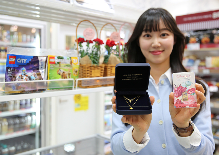 모델이 카네이션목걸이3.75g, 카네이션골드바3.75g 상품을 들고 포즈를 취하고 있다.