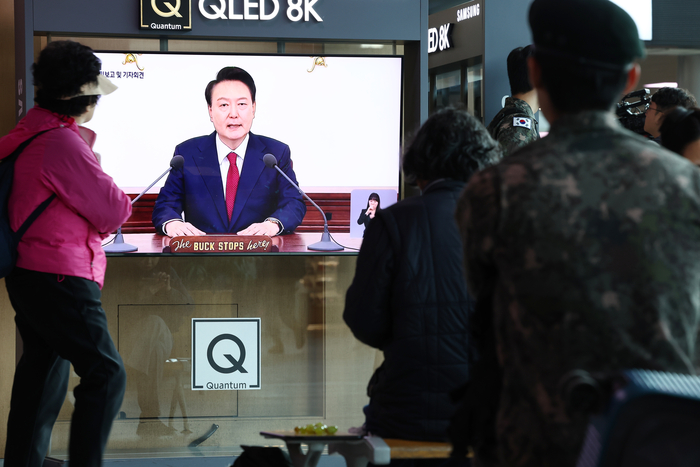 9일 오전 서울 용산구 서울역 대합실에서 시민들이 '윤석열 정부 2년 국민보고 및 기자회견' 방송을 시청하고 있다. 연합뉴스