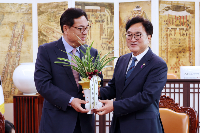 우원식 국회의장(오른쪽)이 10일 오전 국회의장실을 예방한 정진석 대통령 비서실장으로부터 윤석열 대통령이 보낸 축하난을 전달받고 있다. 연합뉴스