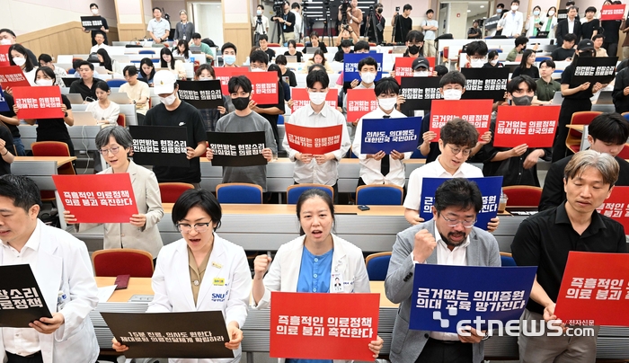 서울대 의대 산하 서울대병원·분당서울대병원·보라매병원·서울대병원강남센터 등 4개 병원 교수들이 무기한 휴진에 돌입했다. 17일 서울 종로구 서울대학교 의과대학에서 열린 '서울대학교병원 교수 휴진 선포 기자회견'에서 의료진이 피켓을 들고 구호를 외치고 있다.
 김민수기자 mskim@etnews.com