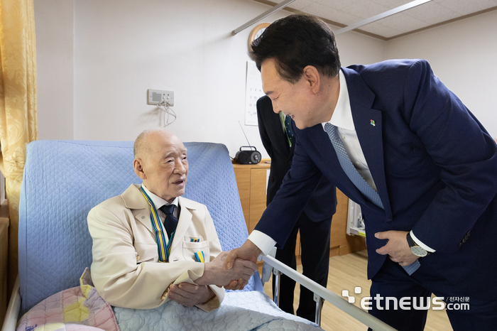 윤석열 대통령이 21일 경기도 수원시 장안구 보훈요양원을 방문해 '영웅의 제복' 재킷을 입은 6·25 참전 국가유공자 이진용 어르신과 인사하고 있다. 대통령실 제공