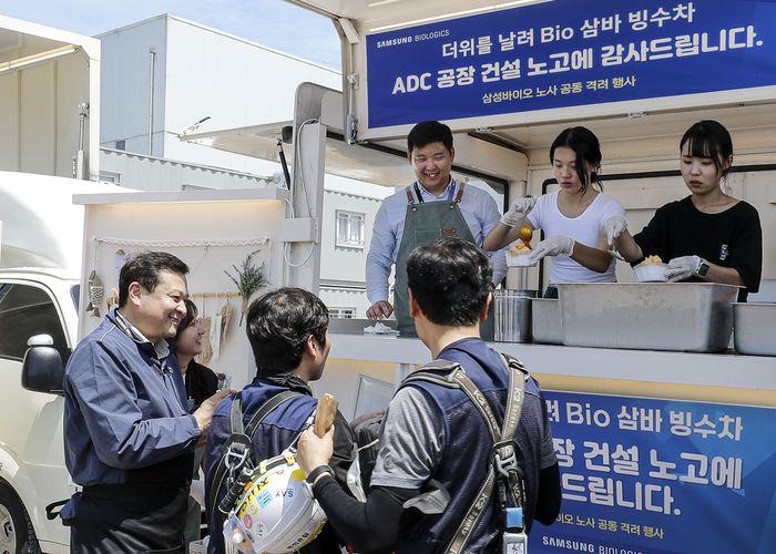 삼성바이오로직스 노사는 19일 인천 송도에 위치한 ADC 공장 건설 현장에서 협력사 기술인 900여명을 대상으로 빙수와 츄러스를 제공하는 상생협력 행사를 개최했다. 이규호 삼성바이오로직스 피플센터 센터장(사진 왼쪽)과 박재성 상생노동조합 위원장(사진 빙수차 안 왼쪽 첫번째)이 빙수차에 방문한 협력사 기술인들을 격려하고 있다.