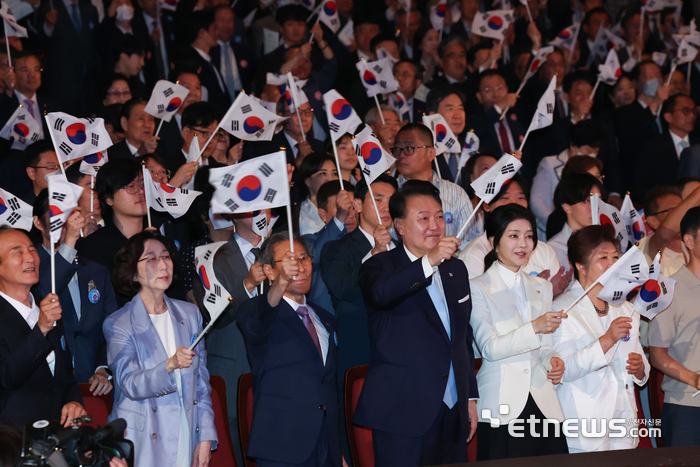 윤석열 대통령과 김건희 여사가 15일 서울 종로구 세종문화회관에서 열린 제79주년 광복절 경축식에서 이동일 순국선열유족회장 등 참석자들과 태극기를 흔들고 있다.
 연합뉴스