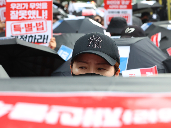 지난 18일 서울 종로구 금융위원회 앞에서 열린 티몬·위메프(티메프) 피해자들의 '검은 우산 집회'에서 참가자가 자리에 앉아 있다. [사진=연합뉴스]