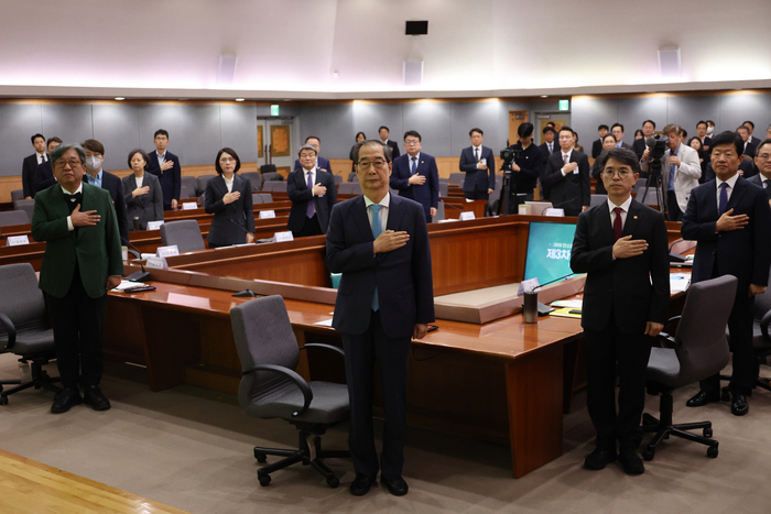 한덕수 국무총리가 30일 서울 종로구 정부서울청사에서 열린 2050 탄소중립녹색성장위원회 제3차 전체 회의에 참석해 국기에 경례하고 있다. 연합뉴스.