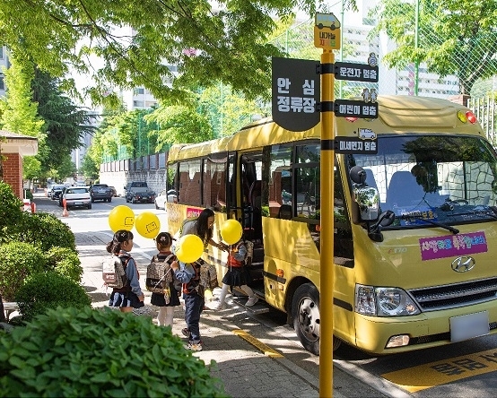 어린이들이 어린이 안심정류장에서 통학차량에 탑승하고 있다.