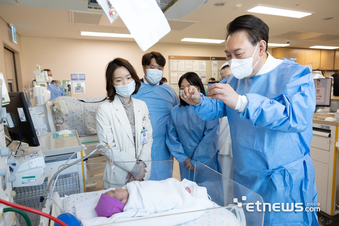 윤석열 대통령이 28일 서울성모병원에서 '이른둥이 지원 간담회' 전 입원 중인 다섯쌍둥이의 다섯째를 보고 있다. 왼쪽부터 주치의 윤영아 교수, 부모, 윤 대통령. 대통령실 제공