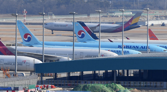 인천국제공항 제2터미널에 계류돼 있는 대한항공 비행기 위로 아시아나항공 비행기가 이륙하고 있다. (자료: 전자신문 DB)