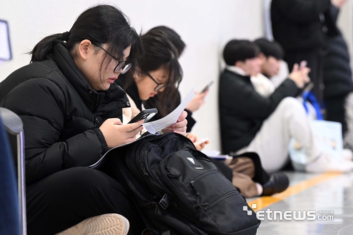 바닥에 앉아서 팜플랫 보는 수험생