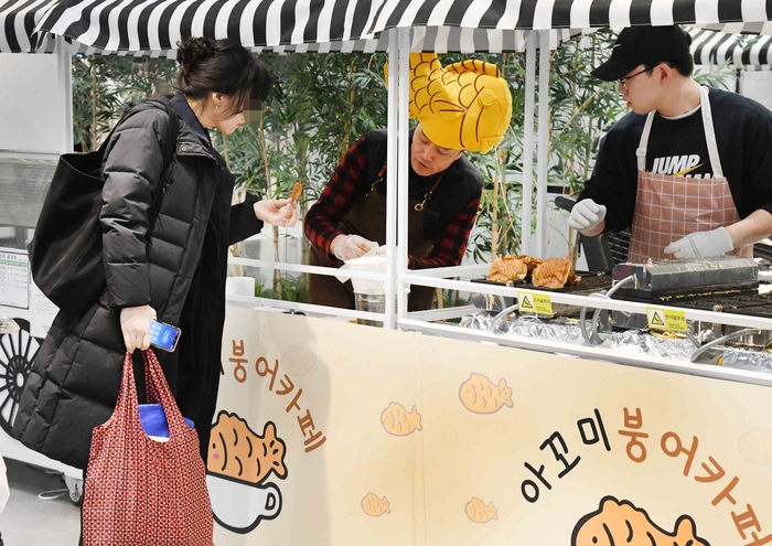 홈플러스 메가 푸드 마켓라이브 강서점 팝업 스토어 아꼬미 붕어빵에서 소비자들이 상품구매 전 시식을 하고 있다.