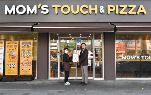 맘스터치 목동점에서 열린 최우수 매장 현판식에서 이진영 맘스터치앤컴퍼니 가맹사업실장(오른쪽)과 이서영 목동점 점주가 기념촬영을 하고 있다. [자료:맘스터치앤컴퍼니]