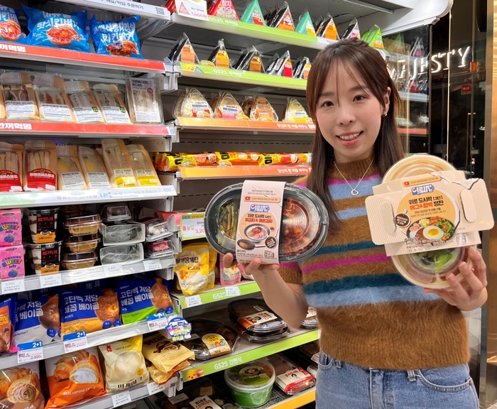모델이 GS25에서 '위로(UP) 도시락' 2종을 들고 포즈를 취하고 있다.