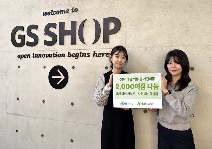GS리테일 직원이 GS샵 스튜디오 앞에서 기부 홍보믈을 들고 있다.