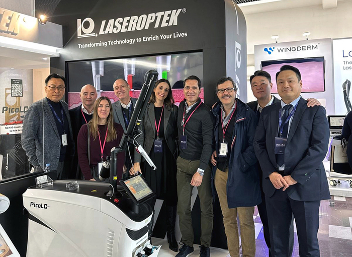 레이저옵텍의 'IMCAS 2025' 전시 부스에서 회사 관계자들이 기념촬영을 하고 있다.