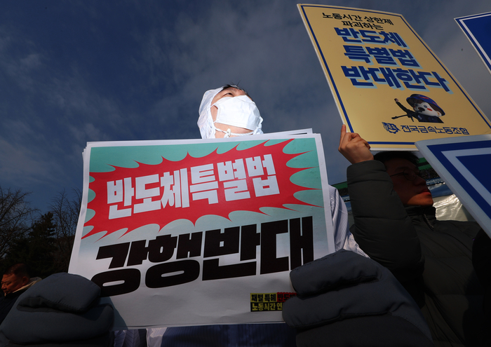 지난 2월 10일 서울 여의도 국회 앞에서 열린 '재벌 특혜 반도체특별법 저지 및 노동시간 연장 반대 공동행동 출범 기자회견'에서 방진복을 입은 참가자가 피켓을 들고 있다. 민주노총 금속노조, 한국노총 전국금속노동조합연맹, 정의당 및 시민사회단체로 구성된 공동행동은 반도체특별법이 노동자들의 노동시간을 늘리고 기후 위기와 환경 파괴를 초래한다며 특별법 제정 중단을 촉구했다. (사진=연합뉴스)