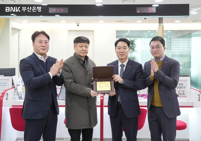 김병기 부산은행 경영지원그룹장(오른쪽 두번째)이 지난 19일 부산은행 일광지점에서 발생한 강도 미수 사건 용의자 검거에 도움을 준 시민 박천규씨(왼쪽 두번째)에게 감사패를 전달하고 있다.