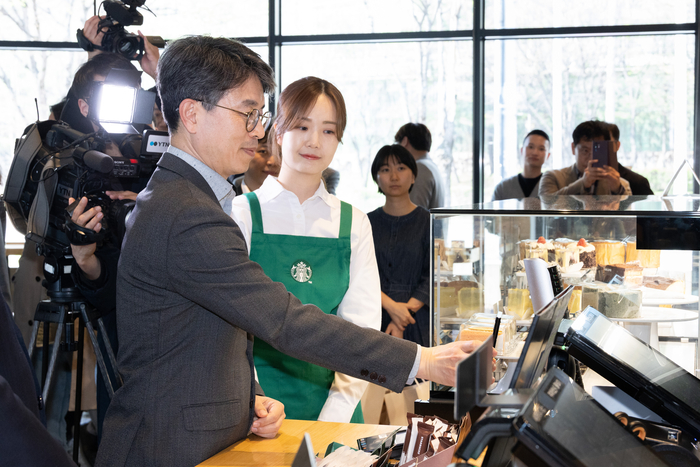 김완섭 환경부 장관이 지난 10일 충북 청주시 소재 스타벅스 청주 분평(DT)점에서 스타벅스·청주시와 함께 '맞춤형 일회용 컵 회수.보상을 위한 자발적 협약'을 체결하고 일회용컵 반납을 통한 에코별 포인트 적립을 체험하고 있다. 사진출처 : 환경부