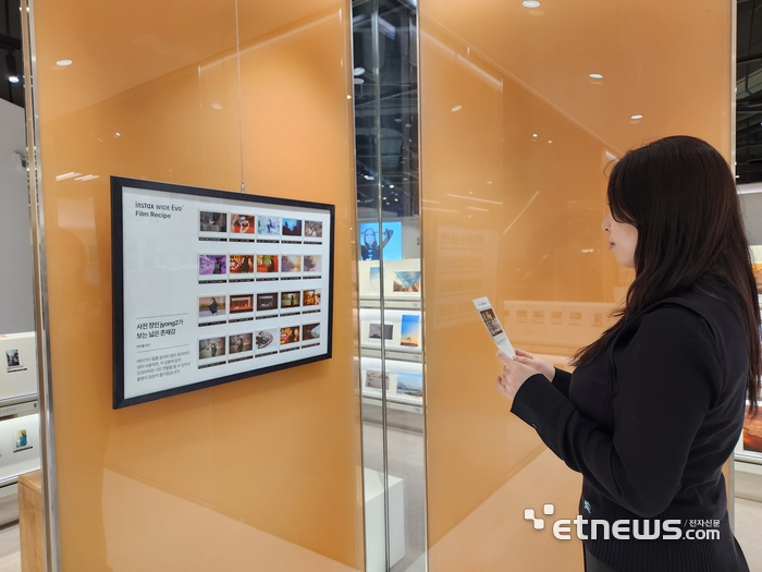 한국후지필름 관계자가 박지홍 작가가 인스탁스 와이드 에보로 찍은 작품을 감상하는 모습. (사진=김신영 기자)
