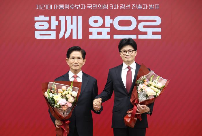 국민의힘 대선 최종 경선에 진출한 김문수(왼쪽)·한동훈 후보가 29일 서울 여의도 당사에서 2차 경선 결과 발표 후 꽃다발을 들고서 기념촬영 하고 있다. 〈연합뉴스〉
