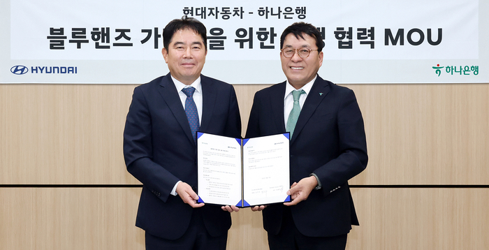 하나은행은 지난 4월 30일 현대자동차와 블루핸즈 가맹점 금융지원을 위한 업무협약을 체결했다. 이날 협약식에 참석한 김진우 하나은행 중앙영업그룹 부행장(사진 오른쪽)이 이용섭 현대자동차 국내사업본부 국내서비스사업부 상무(사진 왼쪽)와 함께 협약서를 들고 기념 촬영을 하고 있다. 사진제공=하나은행